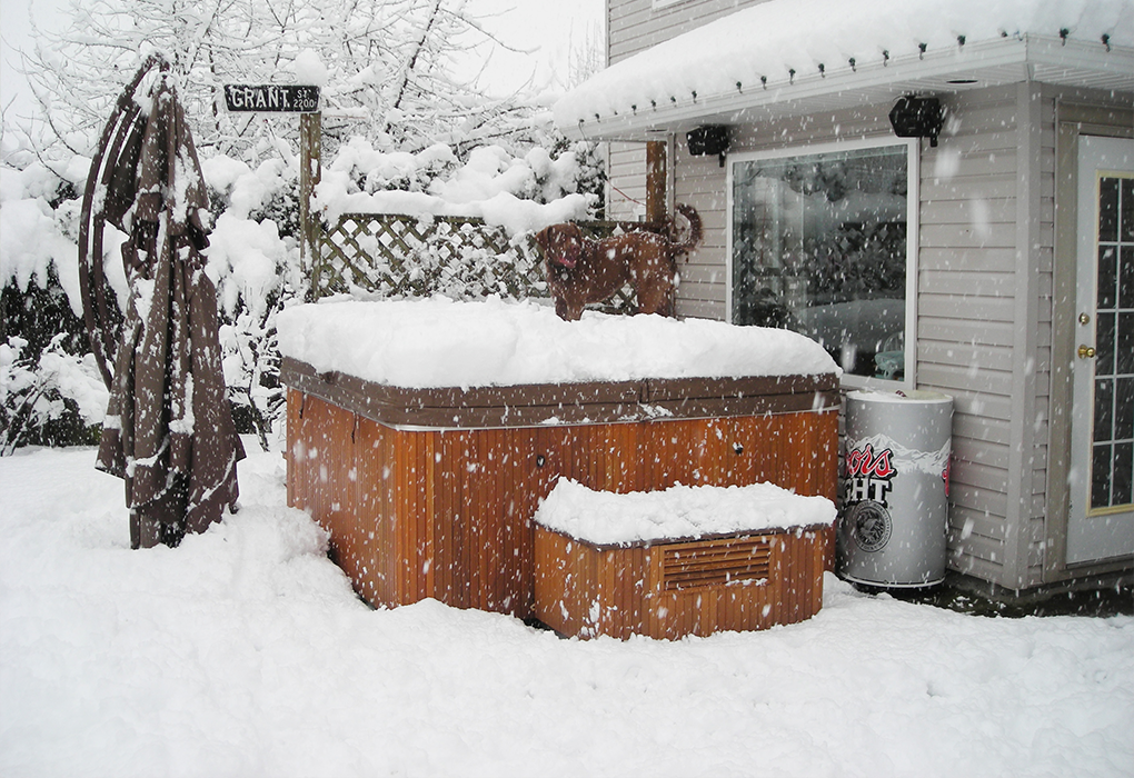 beachcomber hot tub in a snow covered backyard with snow on it 