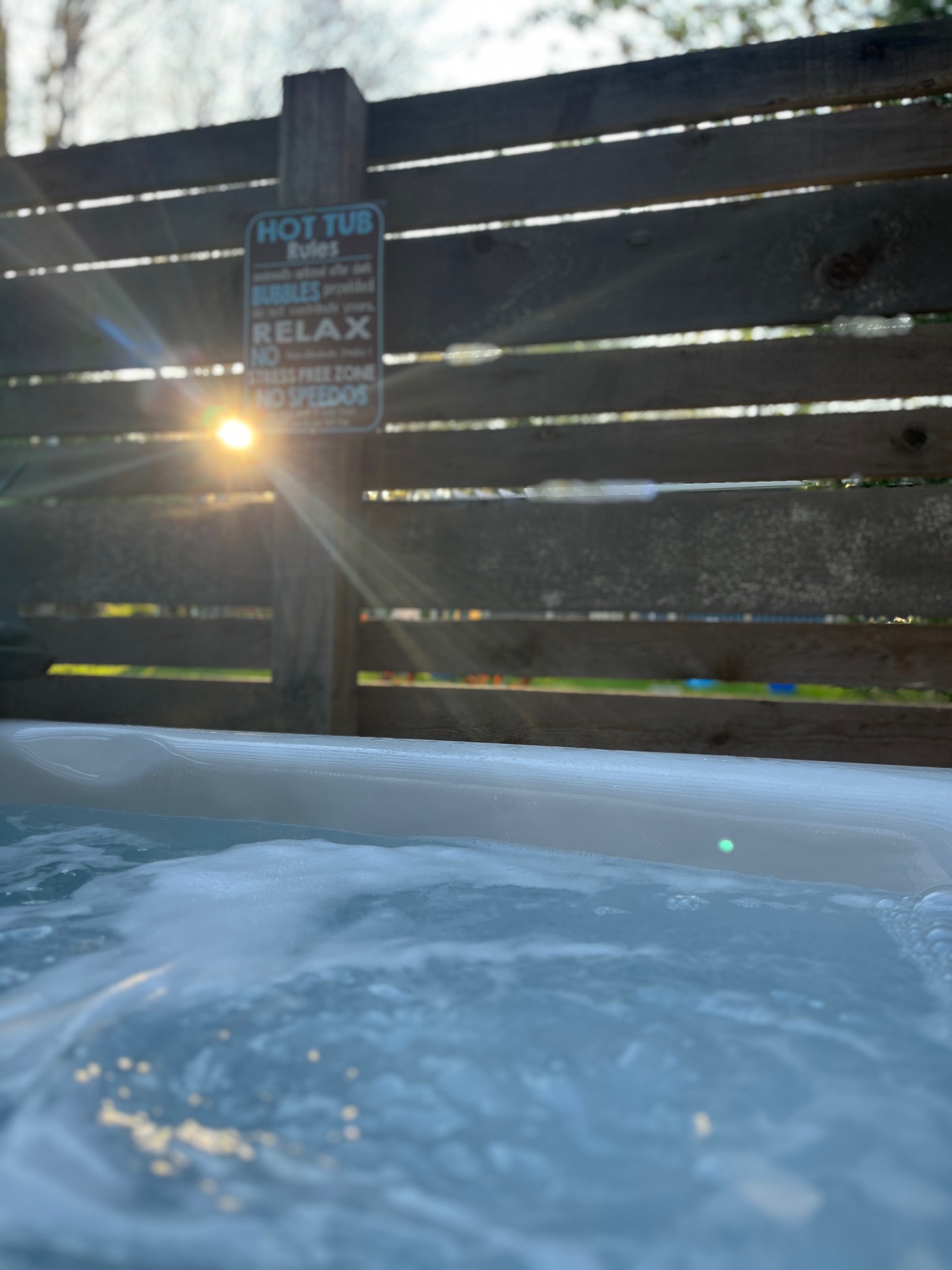 view from within a hot tub with the hot tub water and fence in the backyard