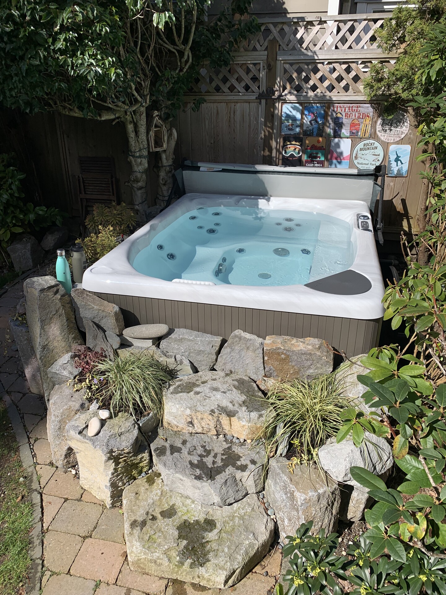 beachcomber hot tub in the corner of a yard with trees and rocks around it